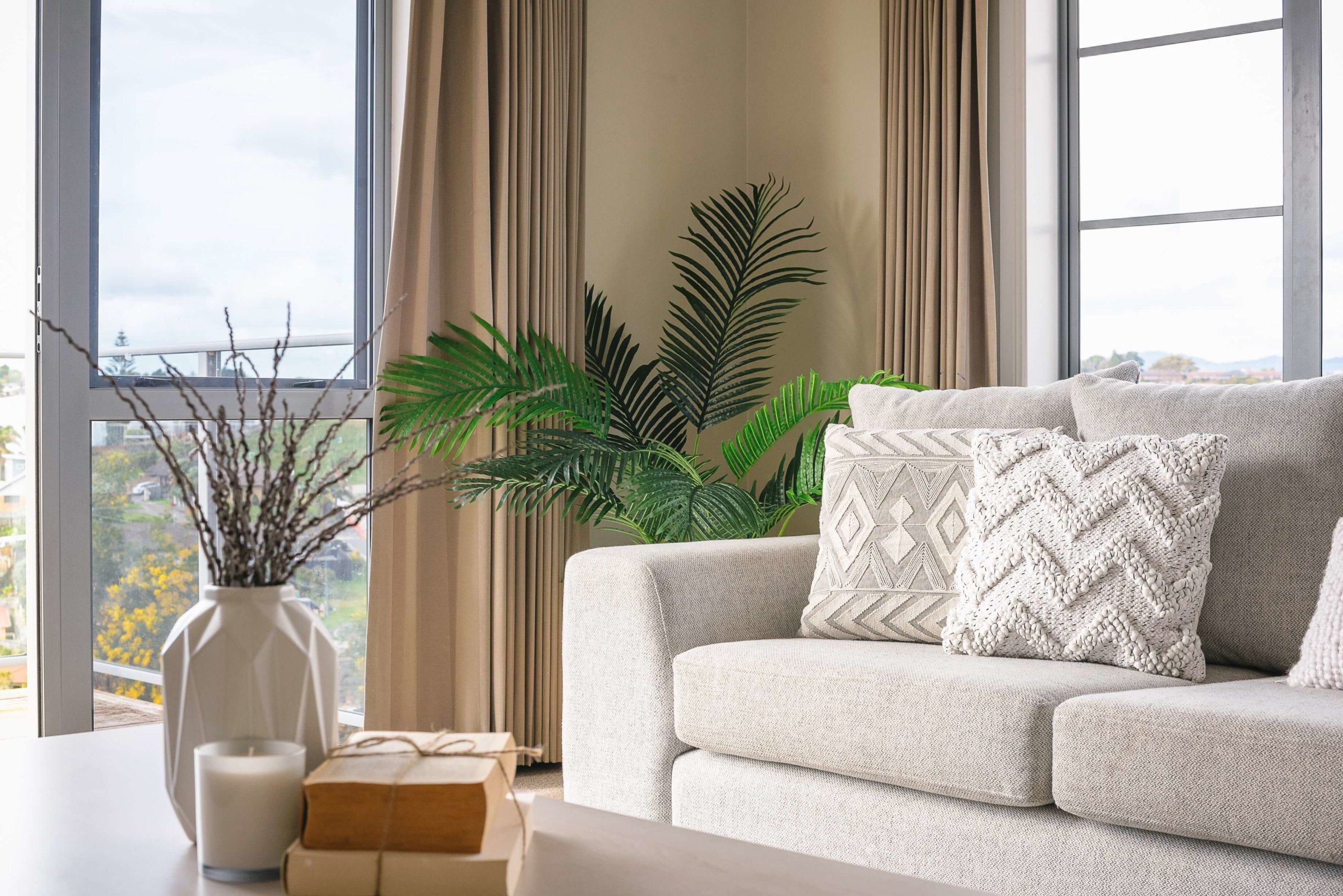 Angolo di un appartamento, arredato con palette neutra, piante e un divano.